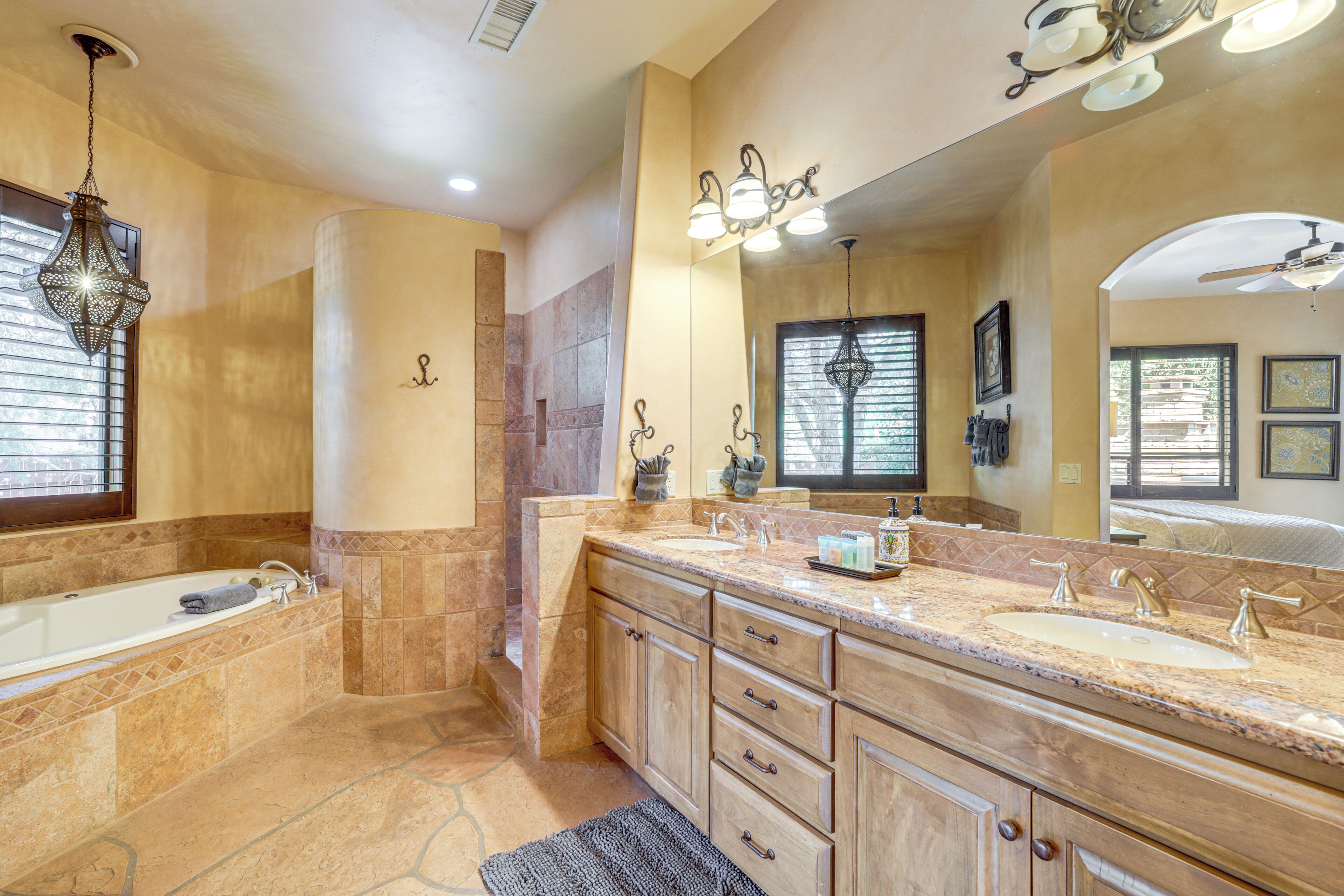 A spacious bathroom with a large bathtub, two sinks, and a vanity with drawers.