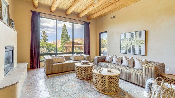 A spacious living room with a fireplace, large windows, and a high ceiling. - 1/2 Mi to Airport Mesa! Hot Tub Haven w/ Mtn Views (Sedona)