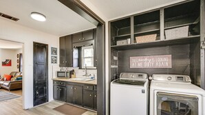 A compact kitchen with dark cabinets, a microwave, and a sign on the wall. - Time Machine: Games Galore in Lubbock Home By Ttu! (Lubbock)