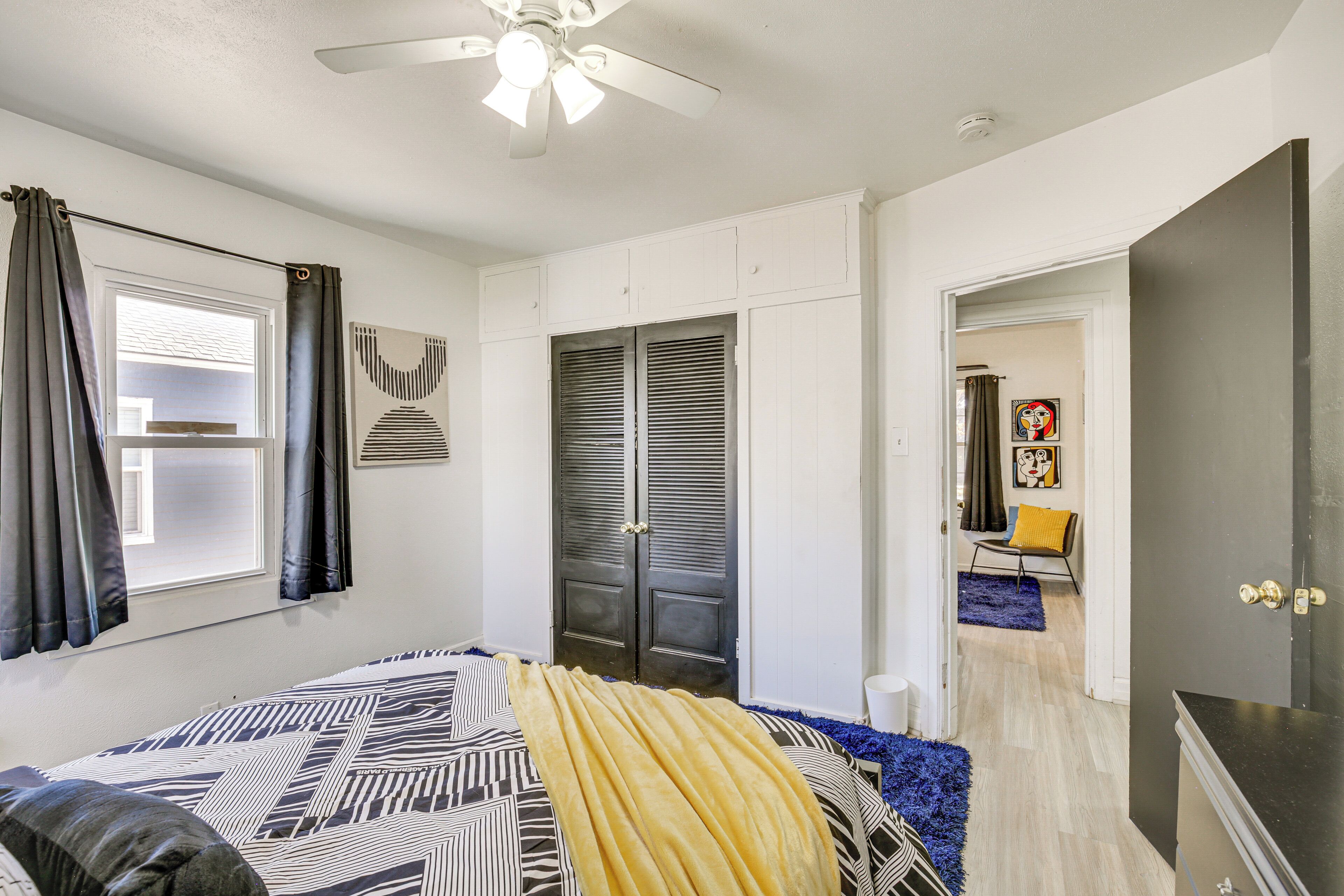 Un dormitorio con cama, ventilador de techo, armario y puerta que da a otra habitación.