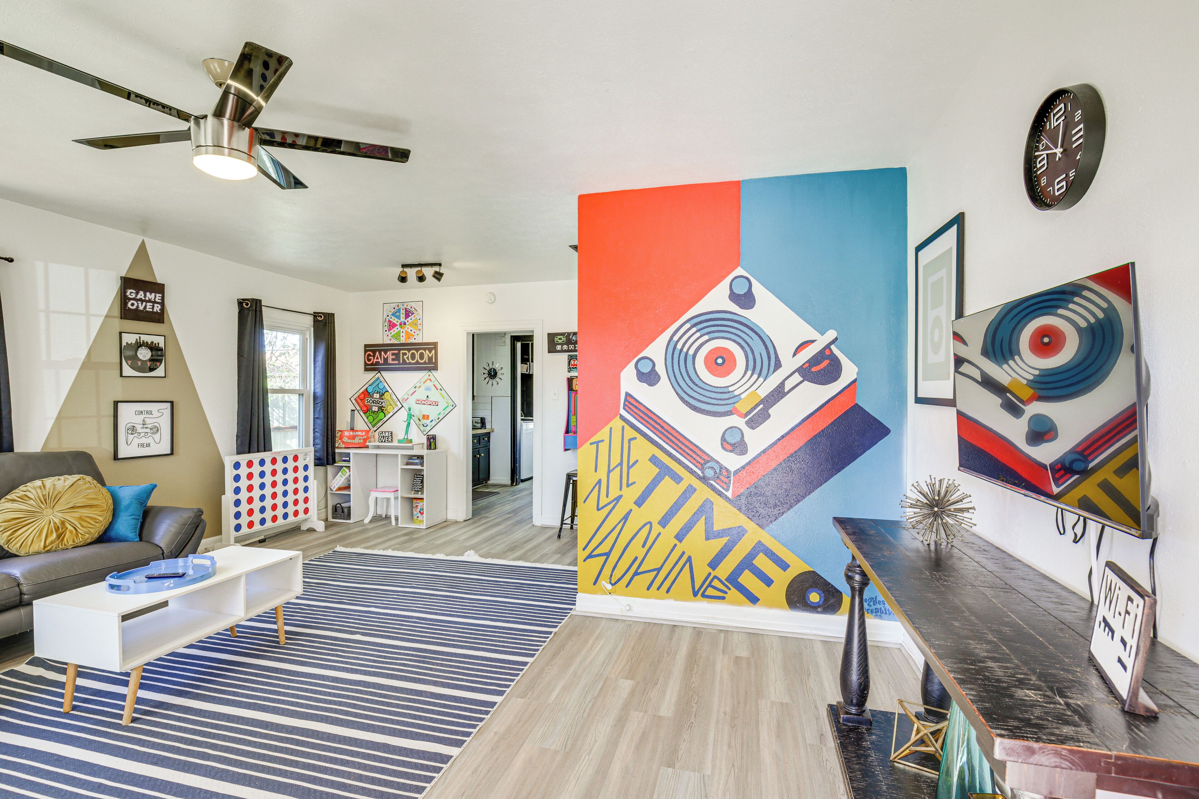 Un salón moderno con un mural grande en la pared, un ventilador de techo y una mesa de centro.