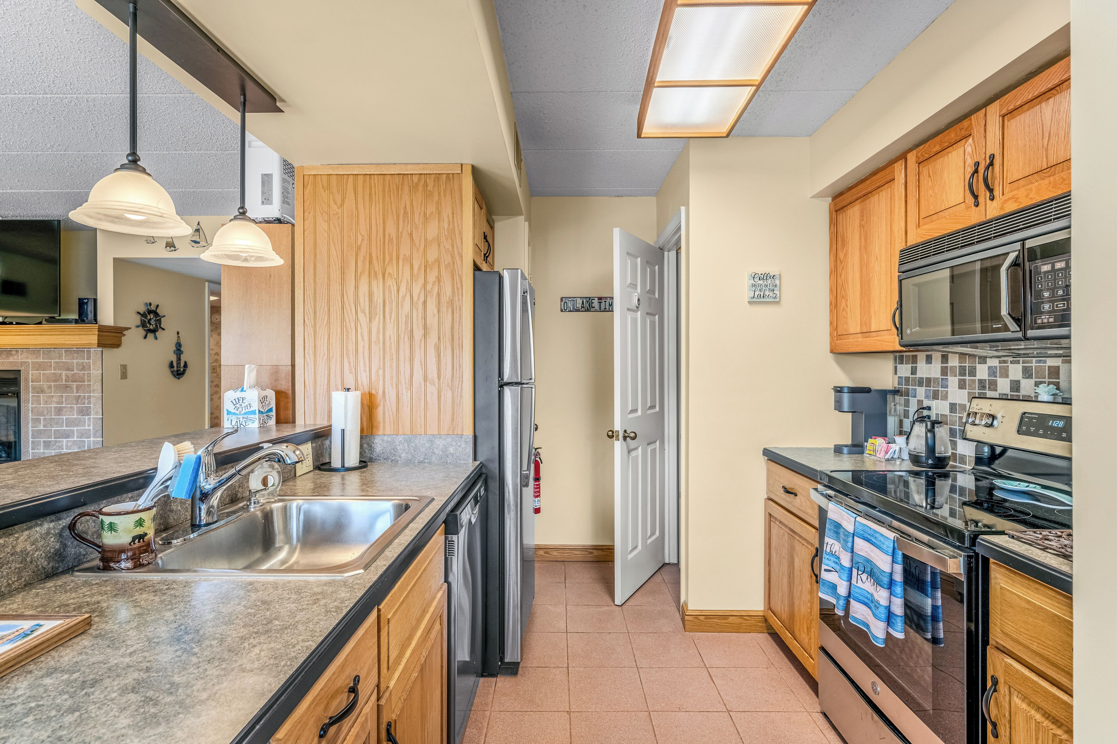 A modern kitchen with granite countertops, stainless steel appliances, wooden cabinets, and a tiled backsplash.