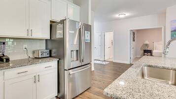 A modern kitchen with white cabinets, stainless steel appliances, and a granite countertop.