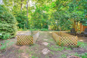 A garden with a wooden lattice fence, brick pathway, and dense foliage. - Private Outdoor Space: Tranquil Home in Greensboro (Greensboro)