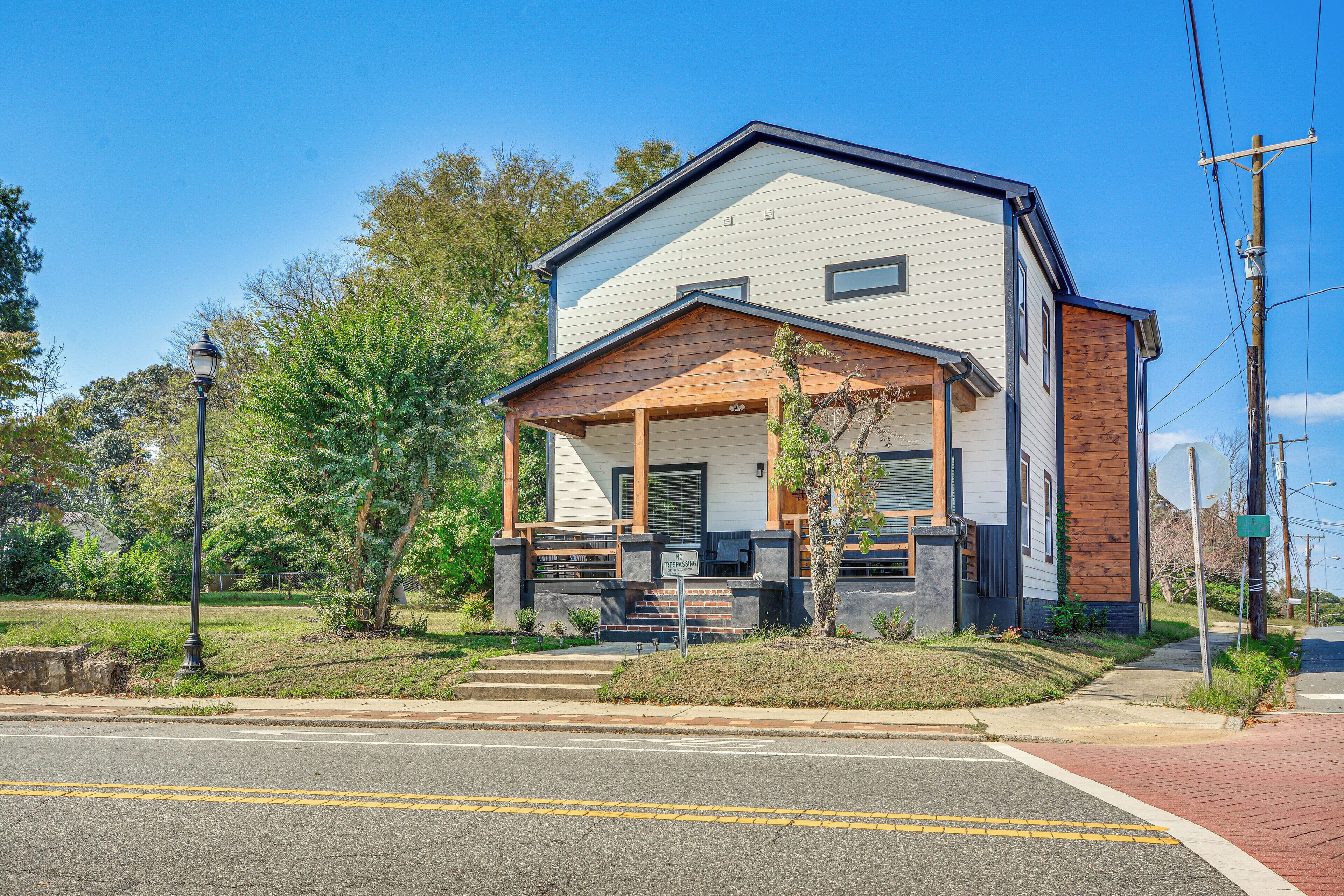 A modern two-story house with a covered porch, a garage, and a landscaped front yard.