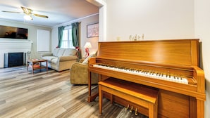 Un salon avec un piano en bois, un canapé, une table basse et une cheminée.