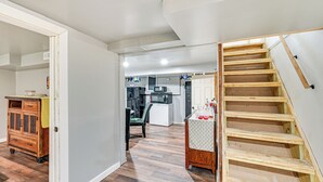 Un vaste espace de vie doté de planchers en bois franc, d’un escalier en bois et d’une cuisine située au fond de la pièce.