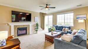 A living room with a fireplace, a sofa, a coffee table, and a television mounted above the fireplace. - 6 Mi to Dtwn Reno: Mtn-view Retreat w/ Fireplace! (Reno)