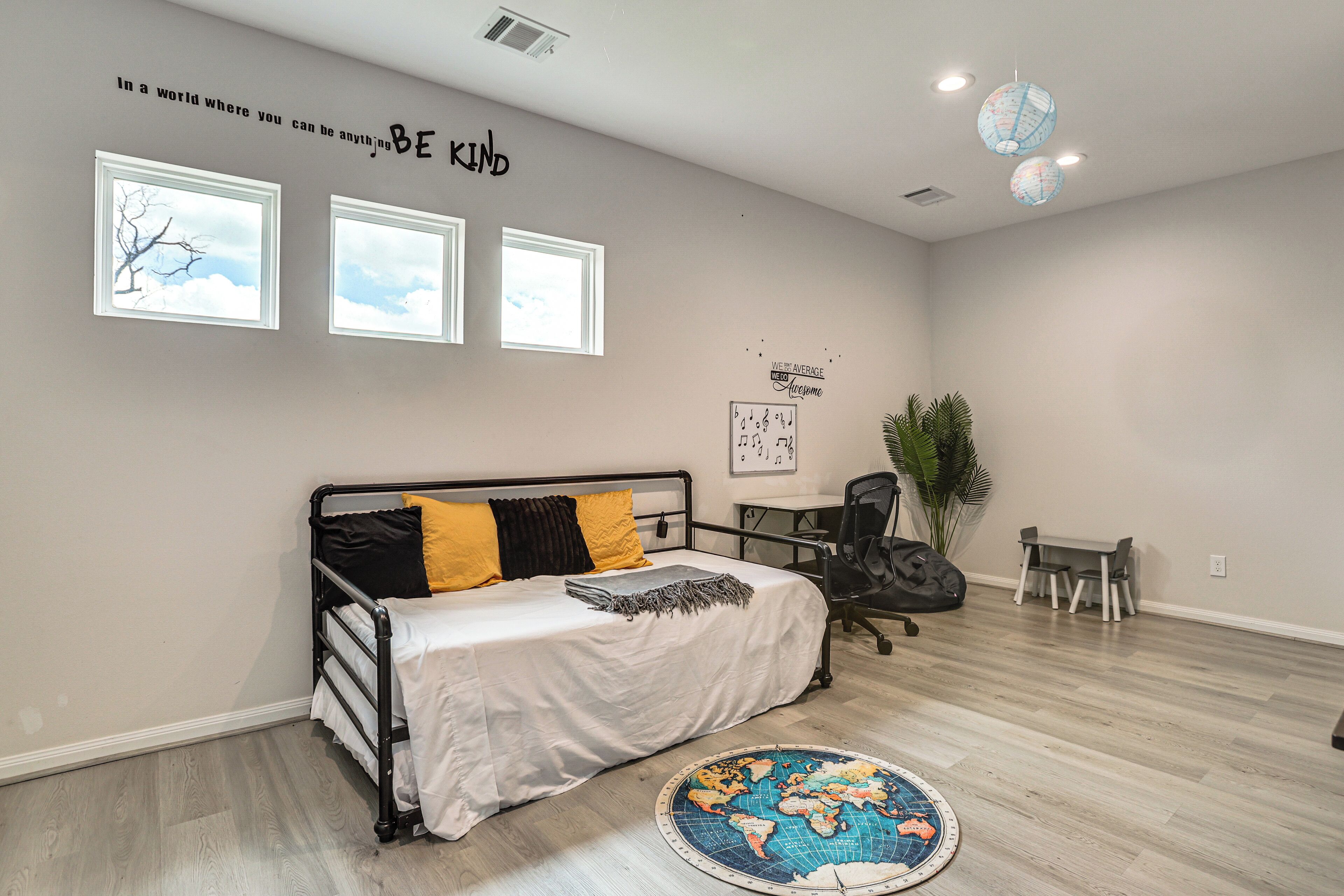 Ein Schlafzimmer mit Bett, Schreibtisch und Teppich mit Globusmuster.