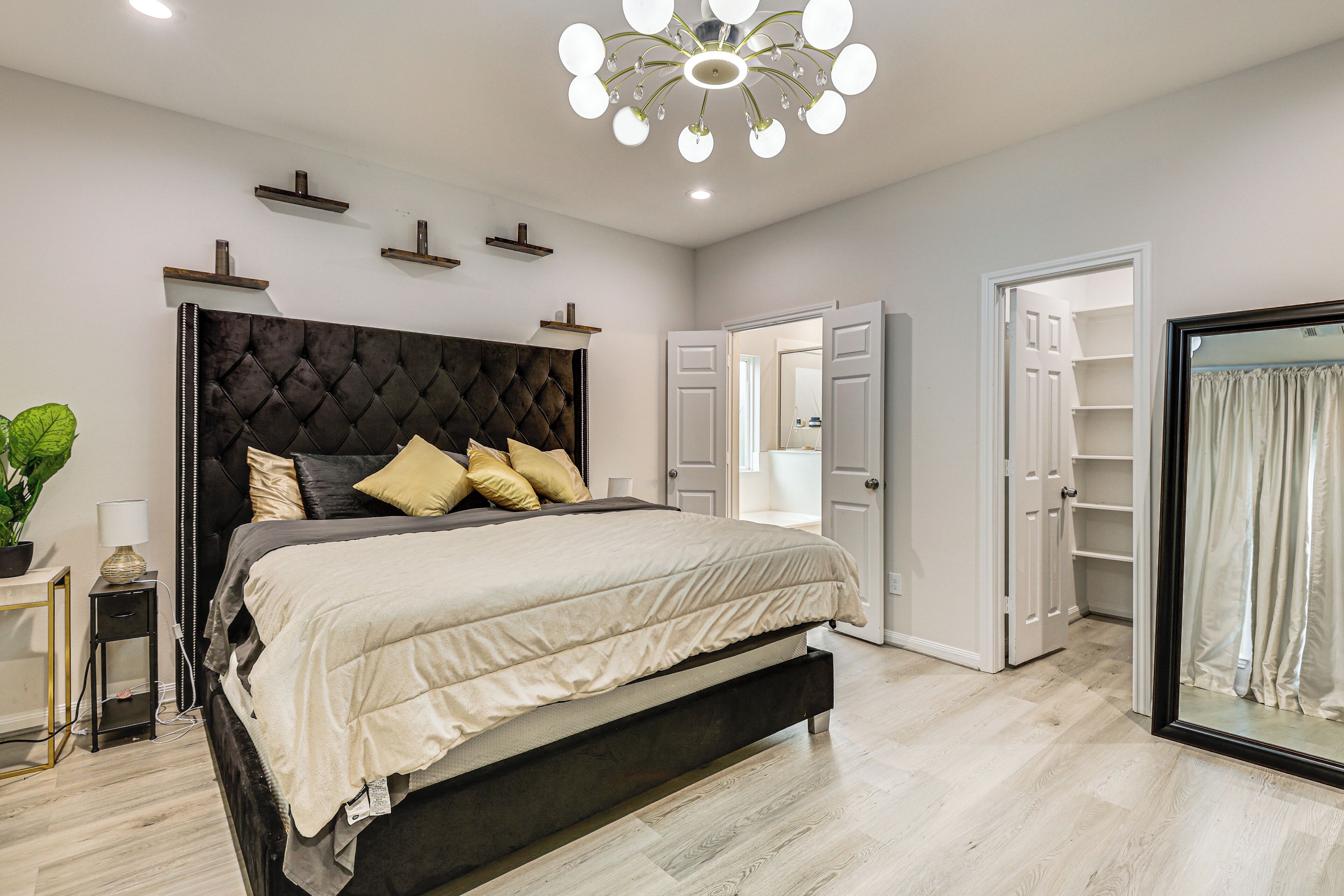Een moderne slaapkamer met een groot bed, een kroonluchter en een inloopkast.