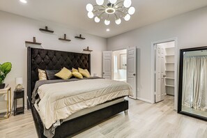 A modern bedroom with a large bed, a chandelier, and a walk-in closet. - 10 Mi to Downtown Houston: Family Home w/ Yard (Houston)