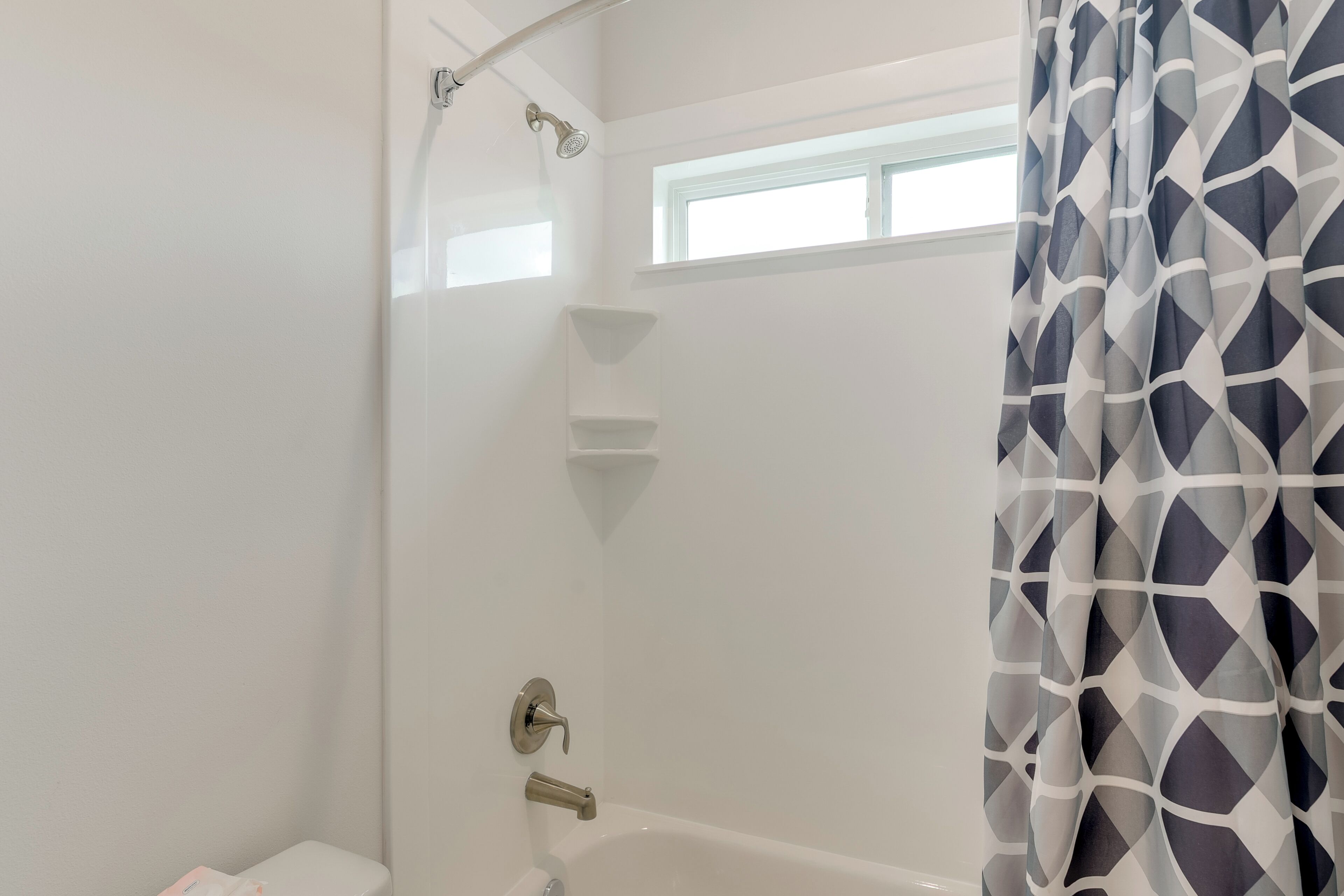 A modern bathroom with a shower, toilet, and a window.