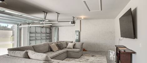 A modern living room with a sectional sofa, a wooden cabinet, and a mounted TV.