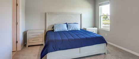 A bedroom with a bed, nightstands, a dresser, and a window.
