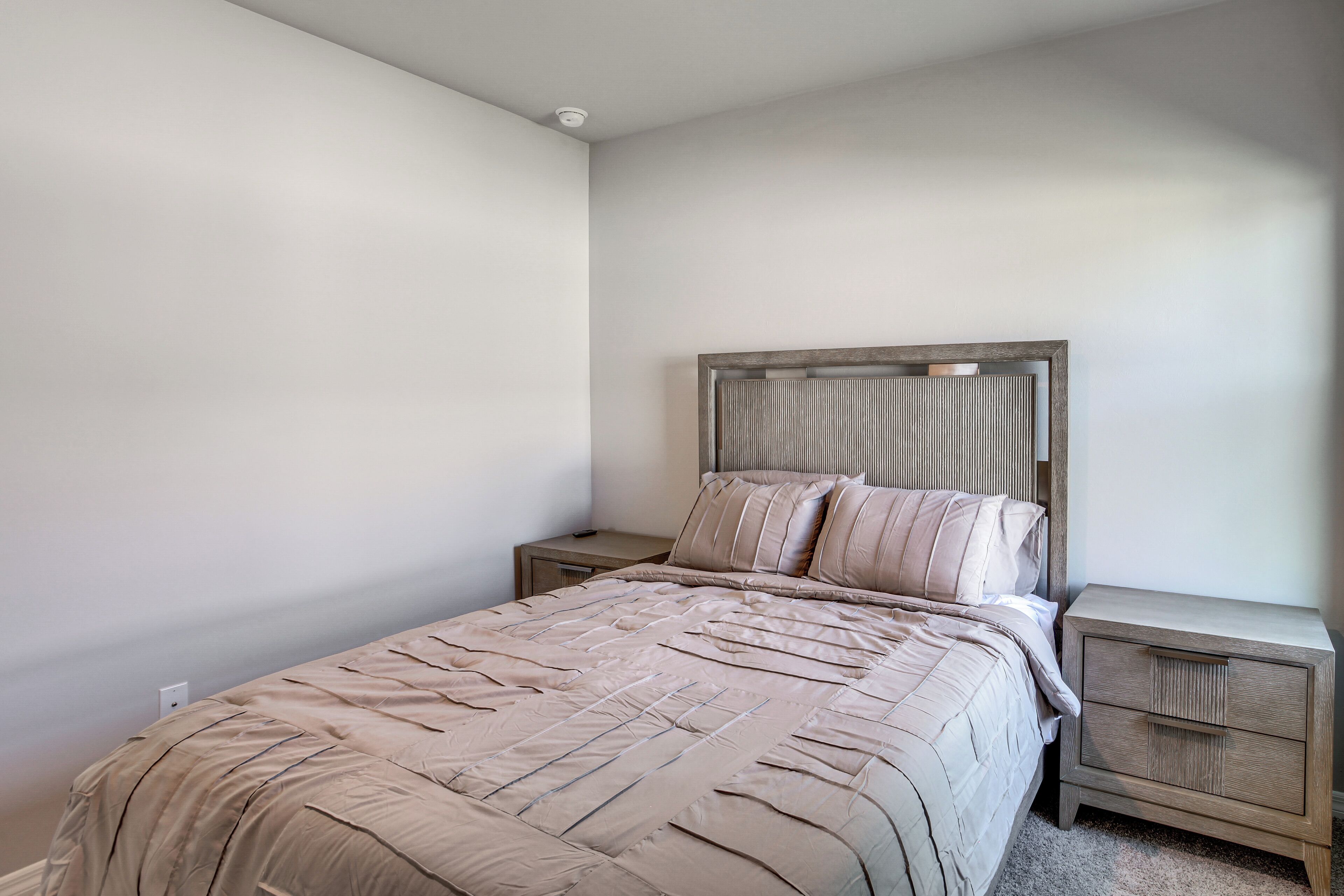 Een slaapkamer met een bed, nachtkastjes en een hoofdbord.