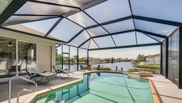 A covered outdoor swimming pool with a view of a lake and distant buildings.