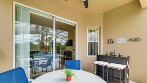 Eine Terrasse mit rundem Tisch, Stühlen, einem kleinen Blumentopf und einer Bar mit Hockern.
