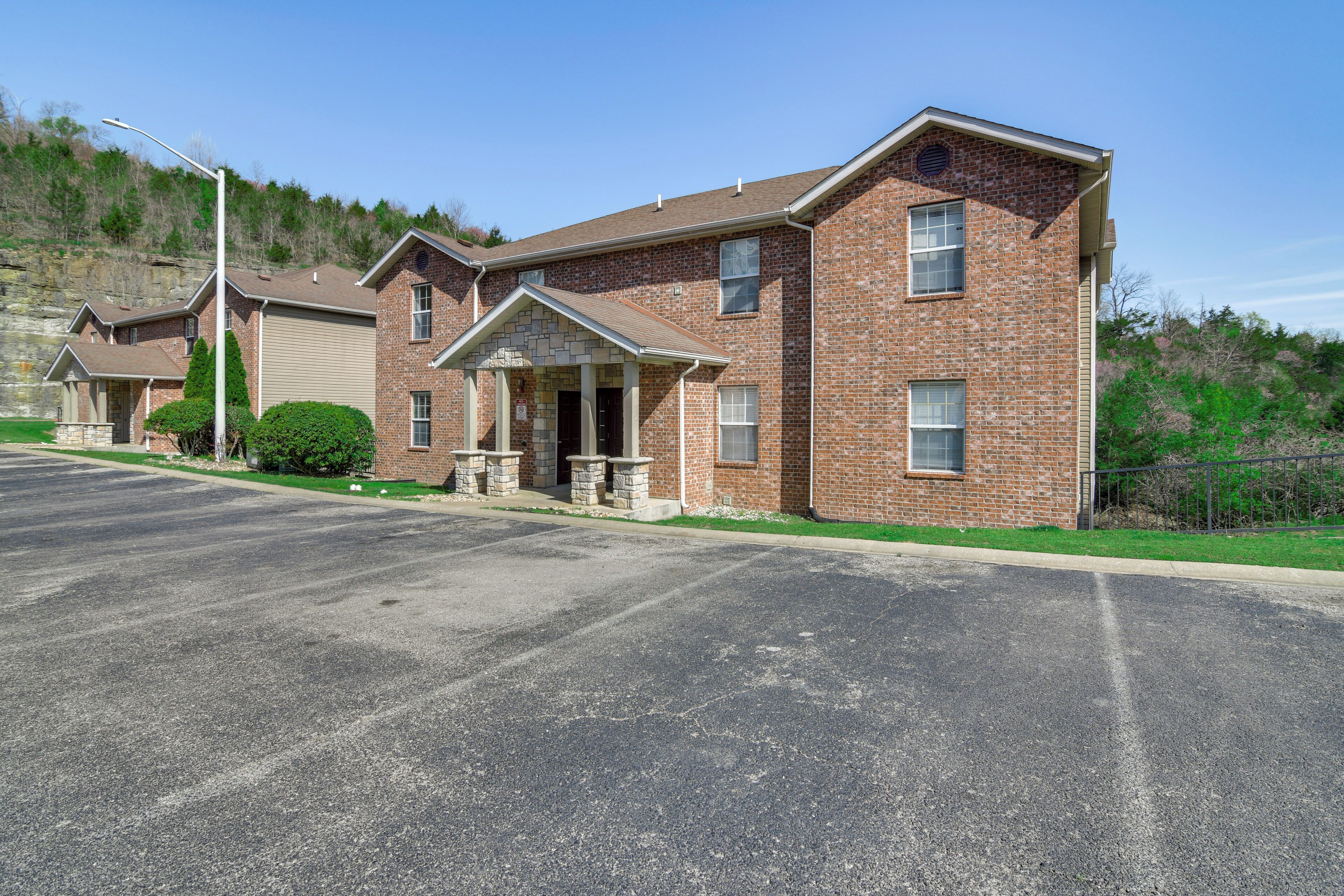 A multi-story brick building with a garage, a covered entrance, and a well-maintained lawn.