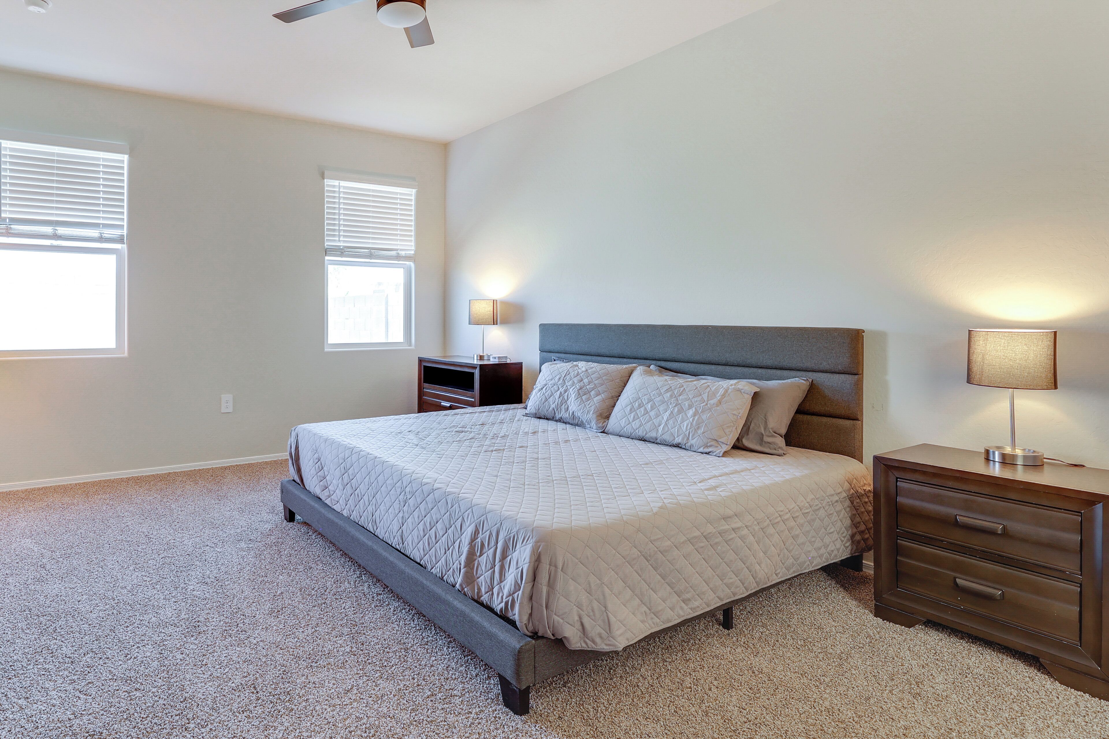 Une chambre à coucher avec un lit, des tables de chevet et un ventilateur de plafond.