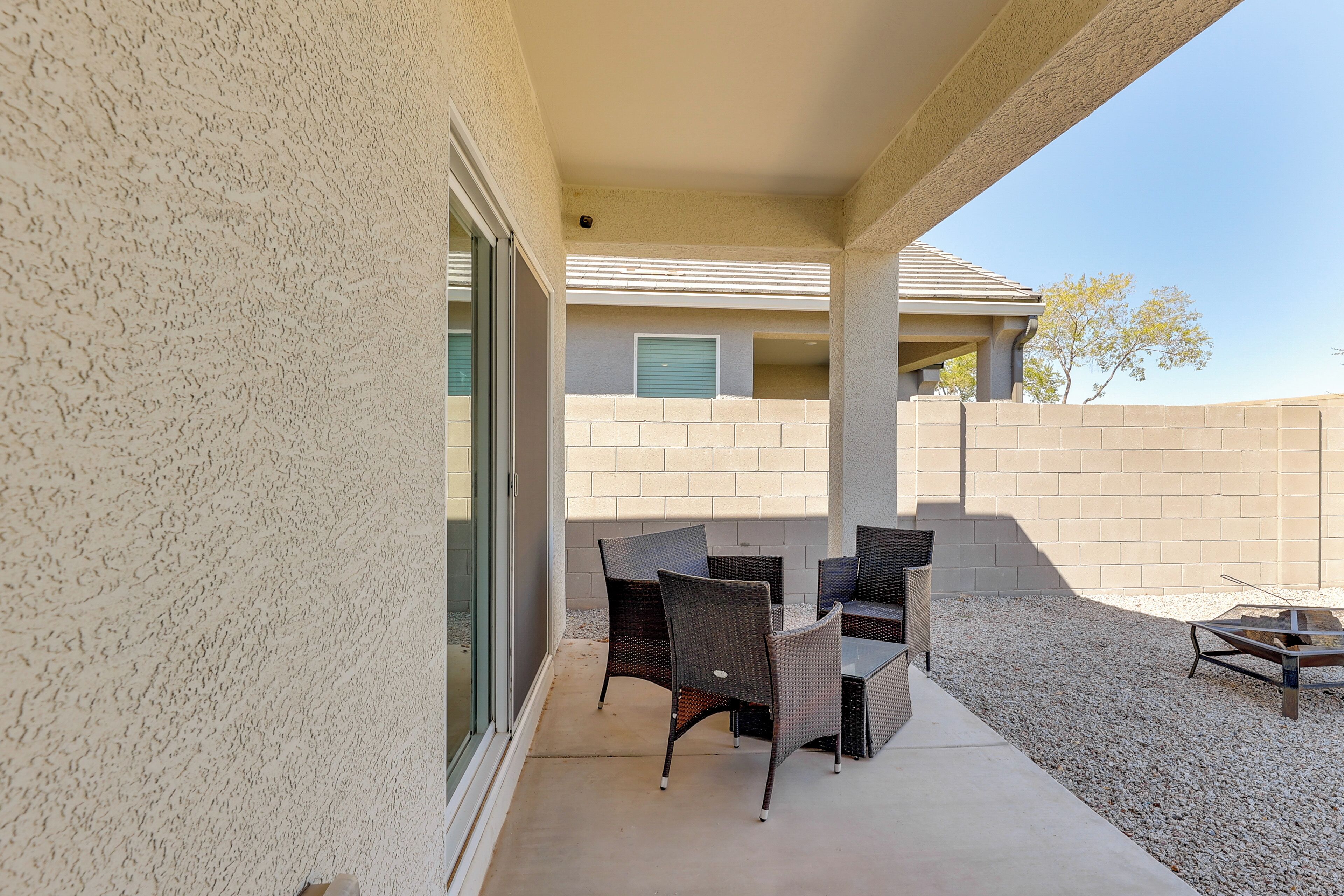 An outdoor patio area with wicker furniture and a fire pit.