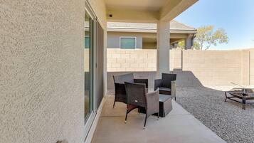 An outdoor patio area with wicker furniture and a fire pit.