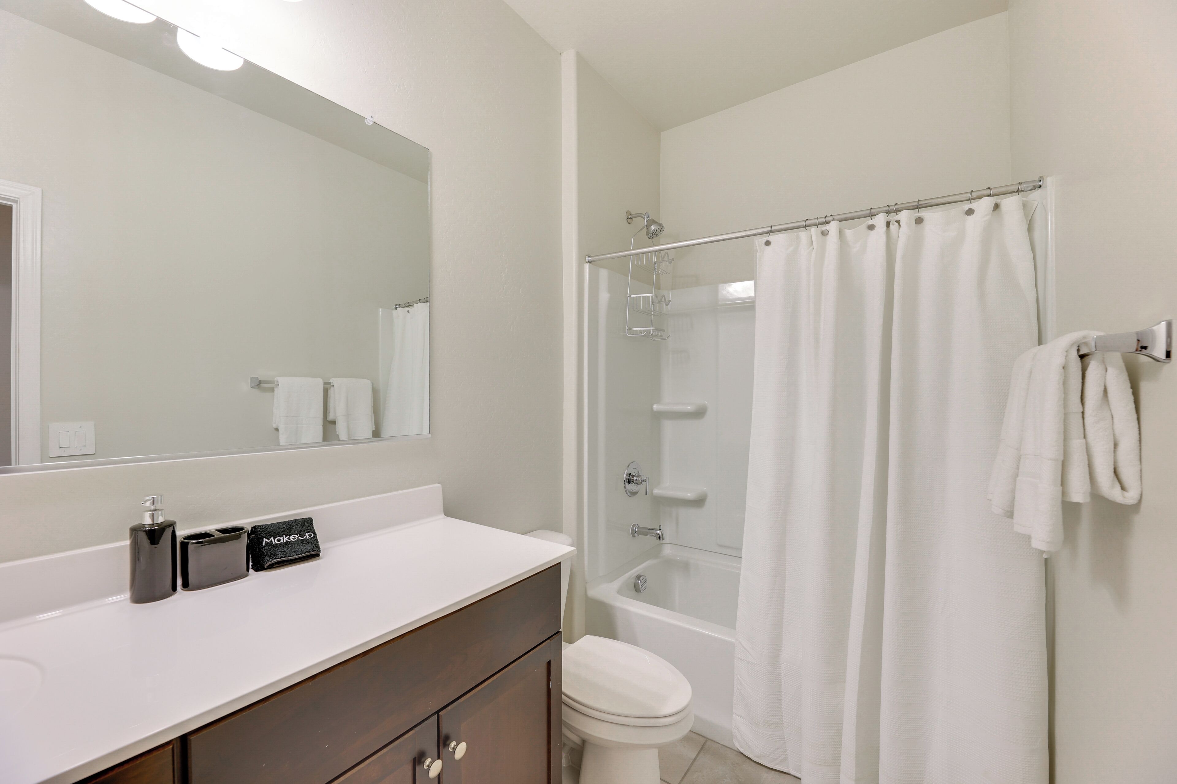 A bathroom with a white sink, a mirror, a toilet, a shower, and a bathtub.