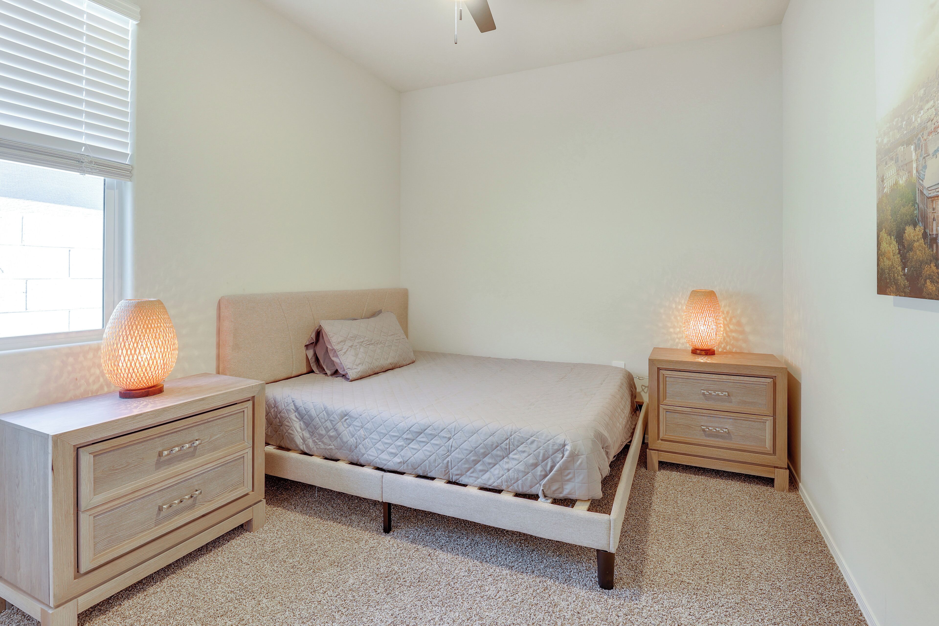 A bedroom with a bed, two bedside tables, and two wall-mounted lamps.