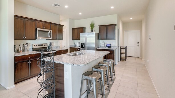 A modern kitchen with granite countertops, stainless steel appliances, and a central island with bar stools.