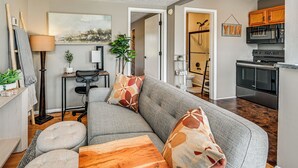 Ein modernes Wohnzimmer mit grauem Sofa, Couchtisch aus Holz und einem Gemälde an der Wand.