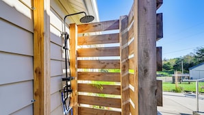 Eine Pergola aus Holz mit an der Wand befestigtem Duschkopf.
