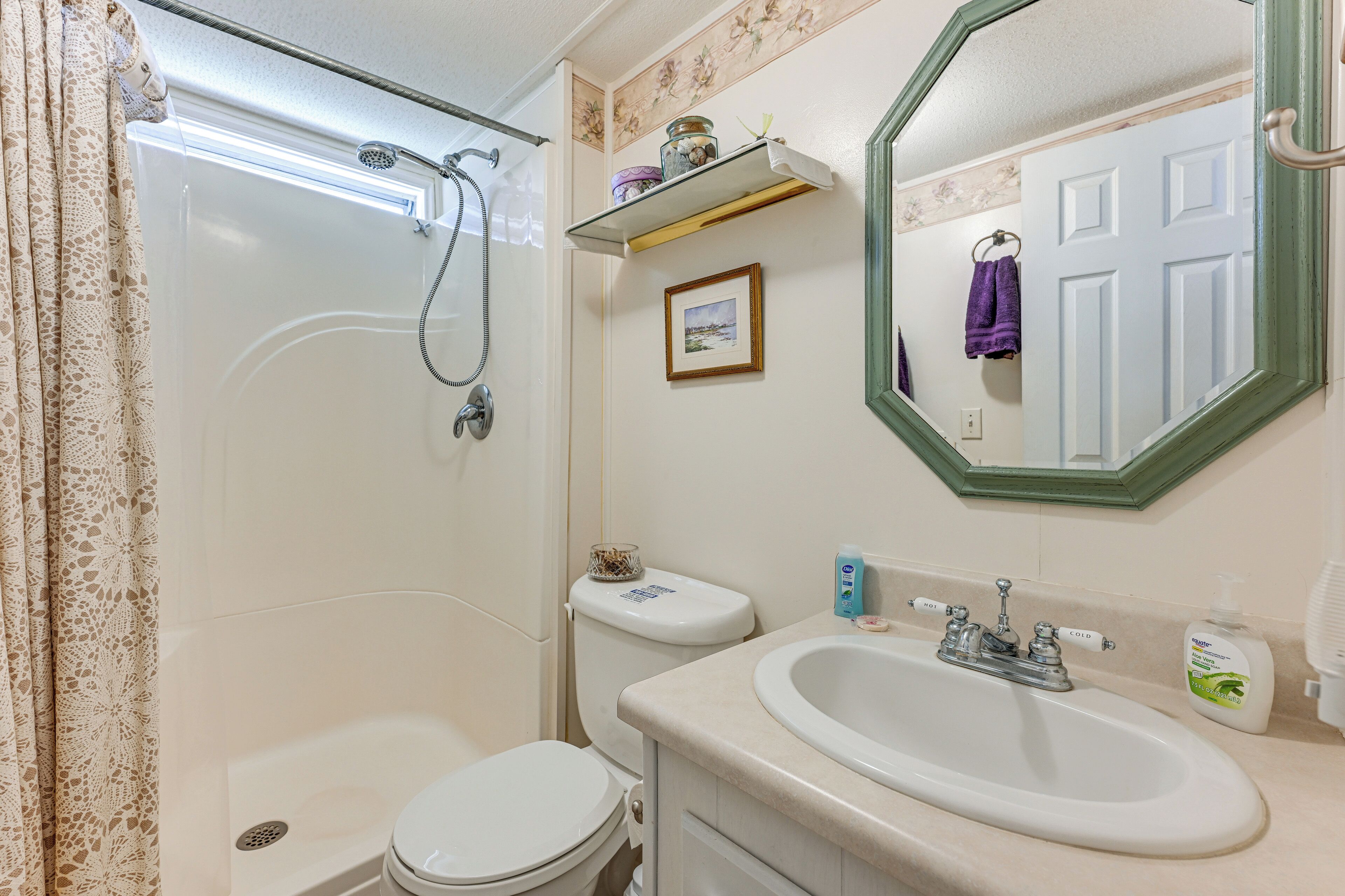 Ein Badezimmer mit Dusche, Toilette, Waschbecken und Spiegel.