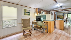 A spacious living room with a wooden floor, a comfortable chair, a wooden desk with a computer, and a kitchen area in the background. - Mine for Gems & Chase Waterfalls: Franklin Retreat (Franklin)