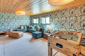 Un salon confortable avec un canapé, un pouf et une table de baby-foot.