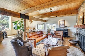 Un salon spacieux doté d’un plafond en bois, de meubles en cuir, d’une cheminée et de grandes fenêtres.