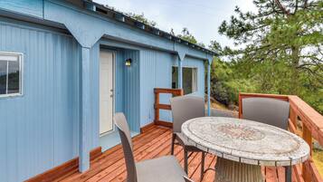A blue building with a wooden deck, a round table with chairs, and a door.
