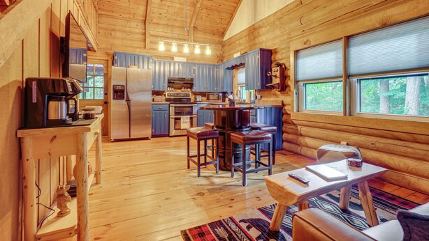 Interior acogedor de una cabaña con cocina, comedor y un amplio ventanal.