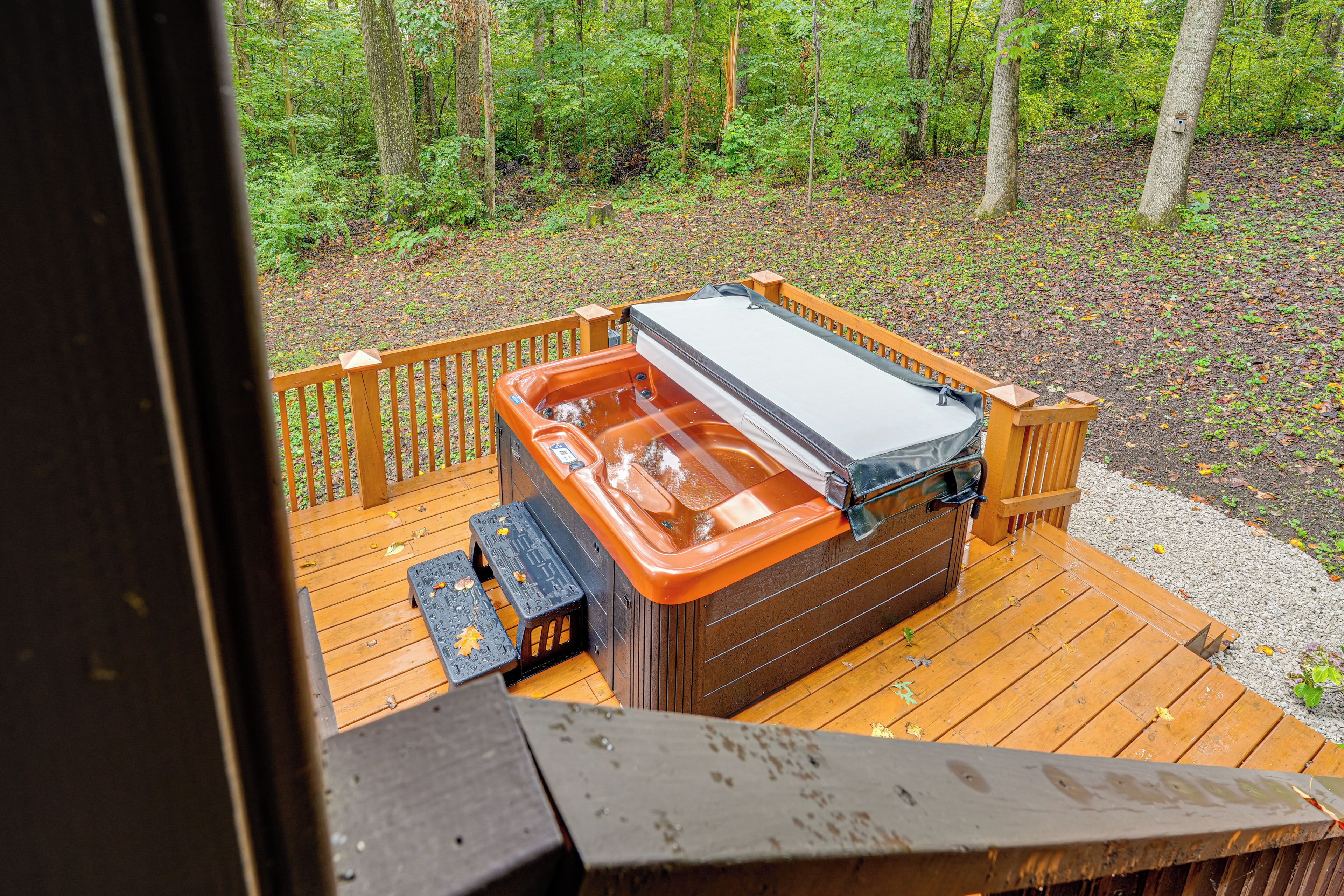 Een hottub op een houten terras met uitzicht op een bos.