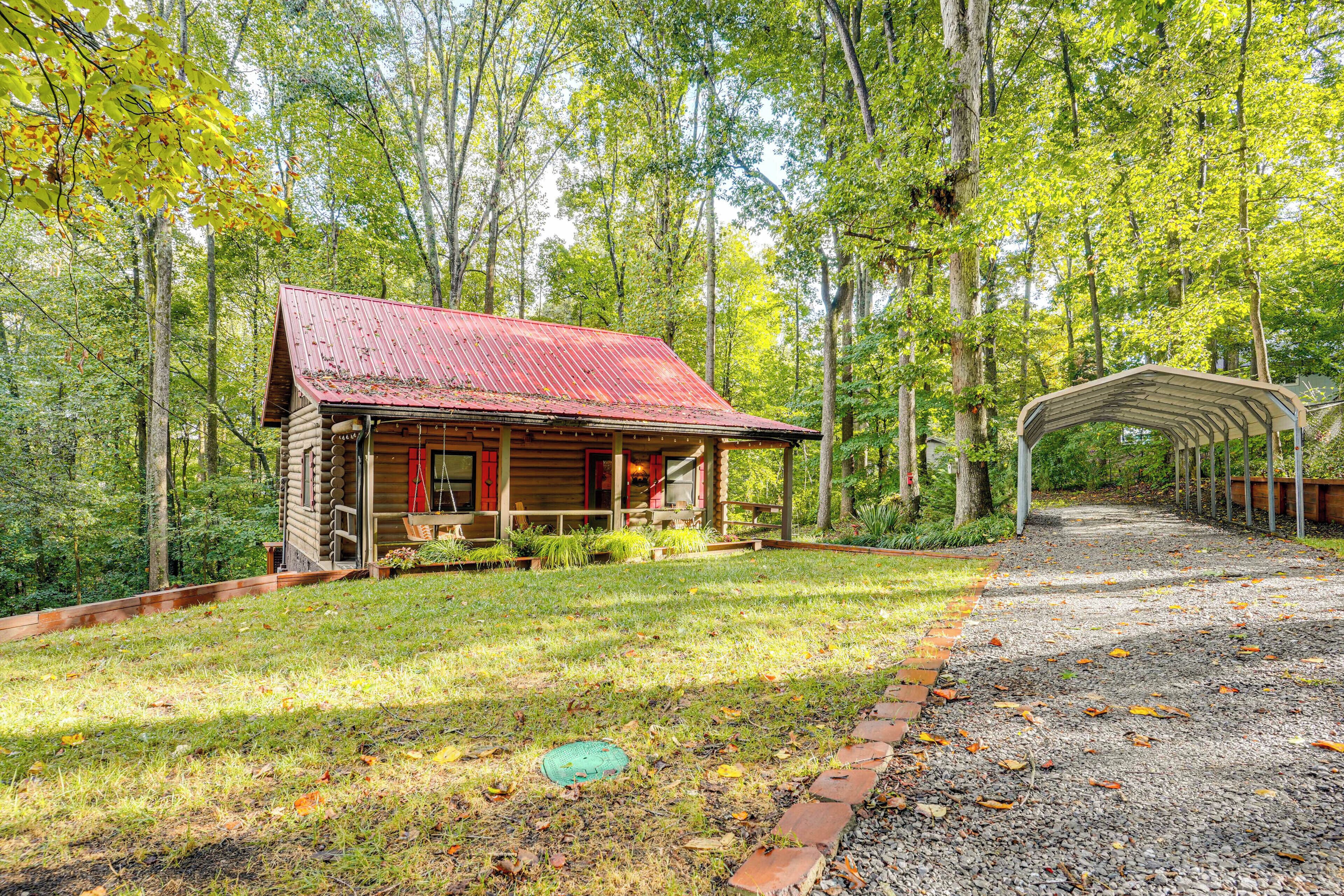 A rustic cabin with a red roof, surrounded by a forest.