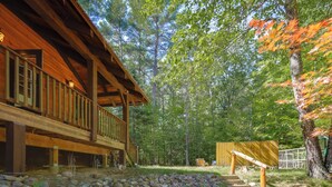 A wooden cabin with a balcony, surrounded by trees and a stone pathway. - Game Room + Lake Access: Wooded Retreat in Jay (Jay)