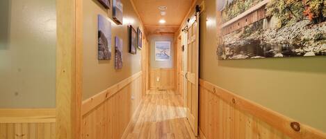 A wooden-paneled hallway with framed pictures on the walls and a large mural depicting a covered bridge.