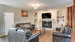A living room with leather sofas, a fireplace, and a television mounted above it.
