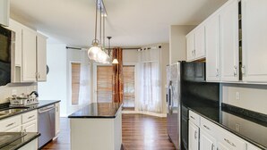 A modern kitchen with white cabinetry, a central island, and a black countertop.