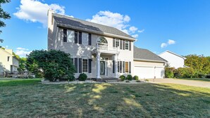 A two-story house with a front porch, a garage, and a well-maintained lawn.