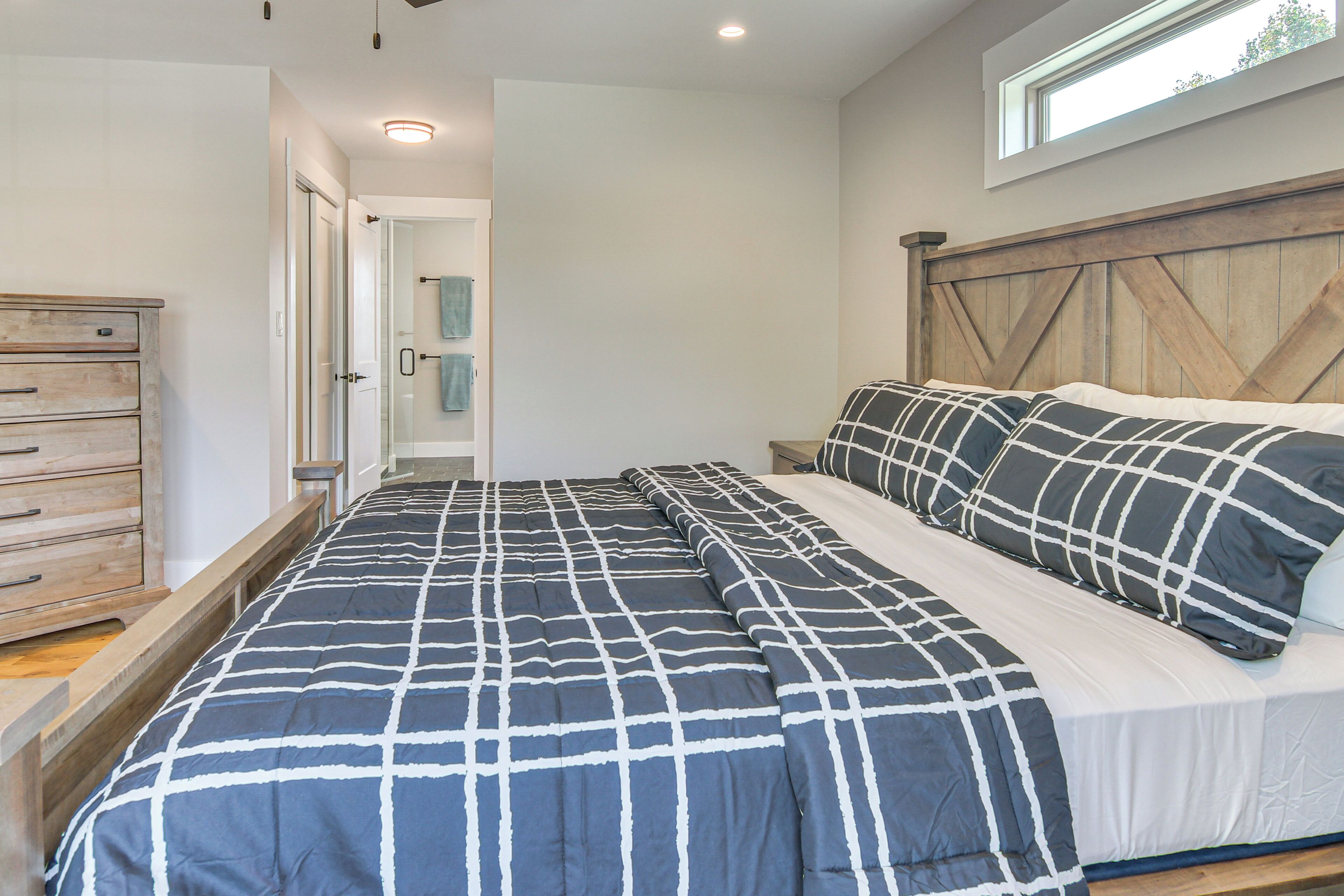 A bedroom with a large bed, wooden headboard, and a view of a bathroom.