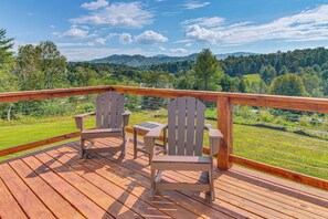 A wooden deck with two Adirondack chairs and a small table, overlooking a green landscape with trees and hills. - 5 Mi to Dtwn, Stunning Views: Weaverville Retreat! (Weaverville)