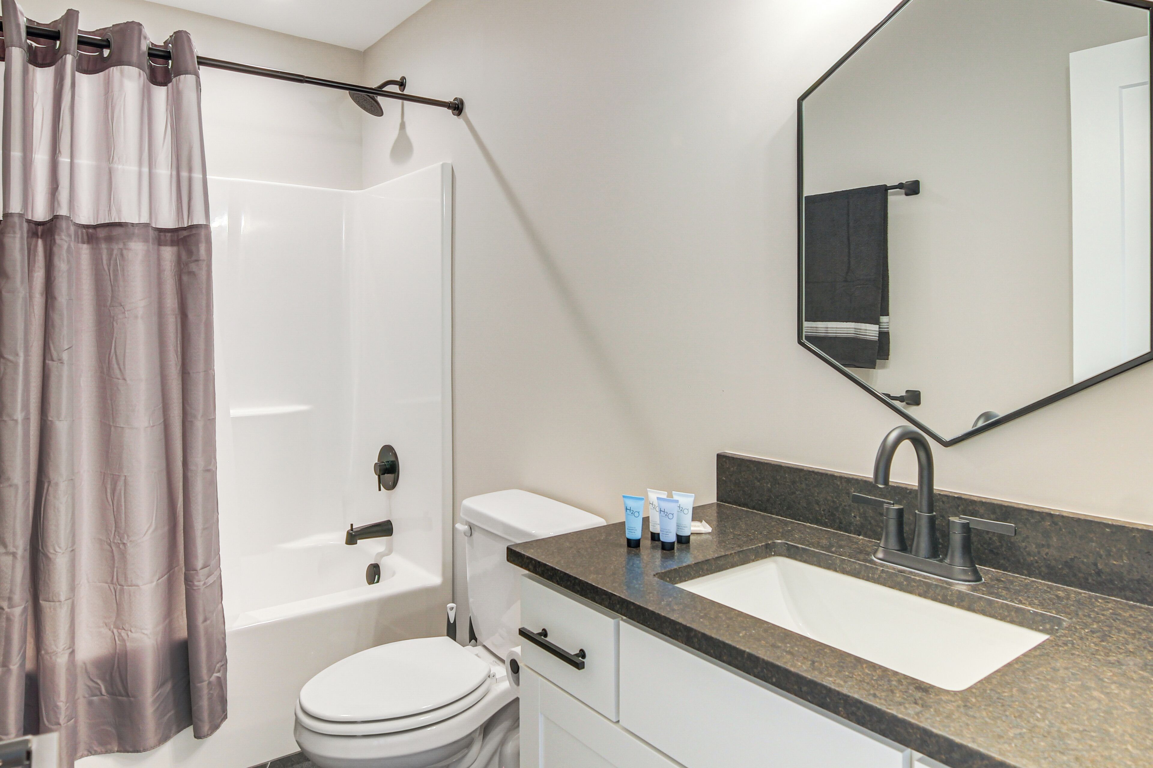 A modern bathroom with a bathtub, toilet, sink, and a large mirror.