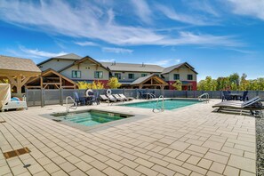 Un espace piscine comprenant deux piscines, des chaises longues et un coin salon abrité.