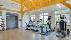 Un gimnasio con cintas de correr, elípticas y pelotas de ejercicio.