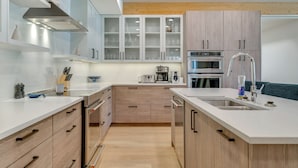 Una cocina moderna con armarios blancos, un lavamanos de acero inoxidable y electrodomésticos integrados.
