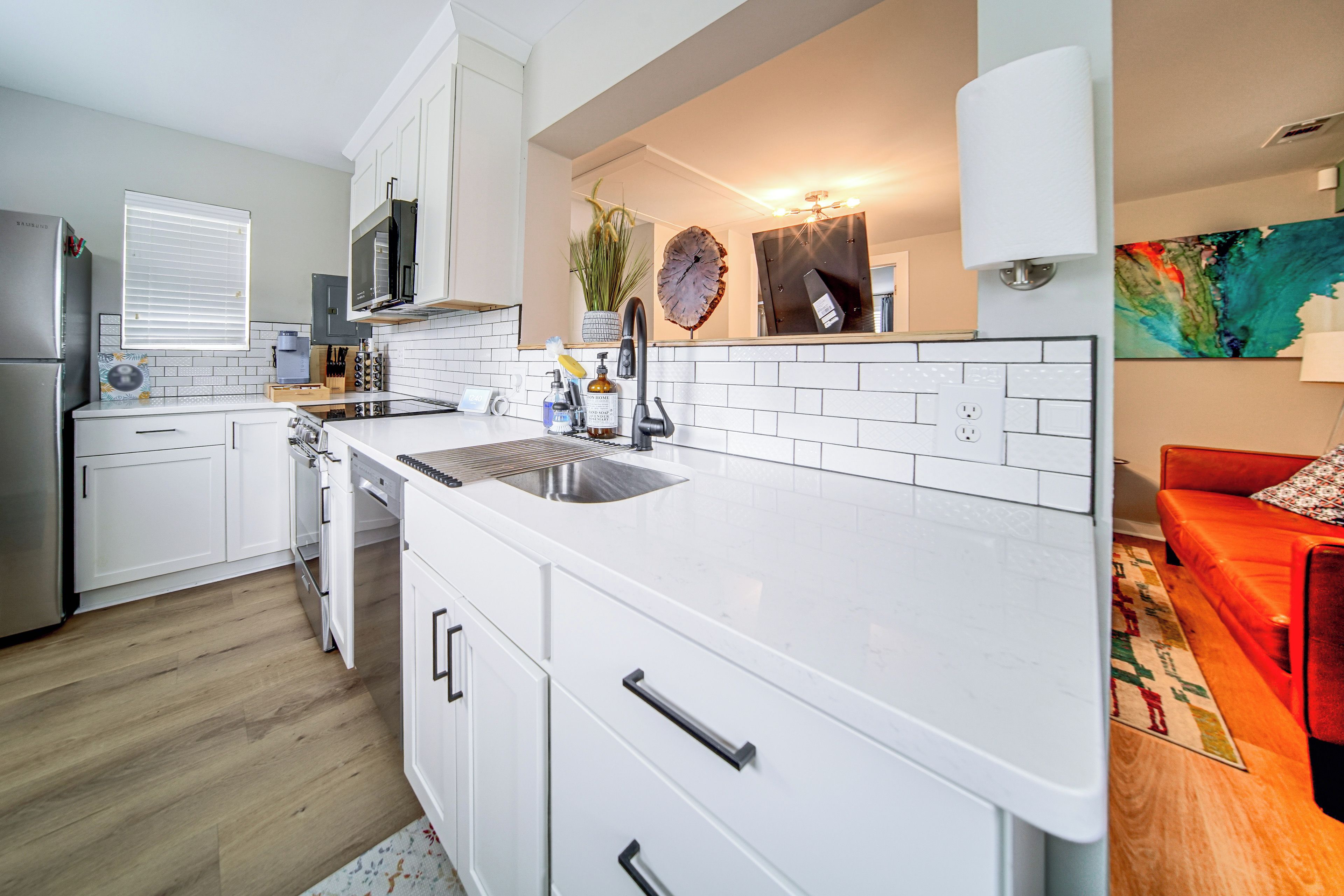 Een moderne keuken met witte kasten, een roestvrijstalen spoelbak en een inbouwoven.